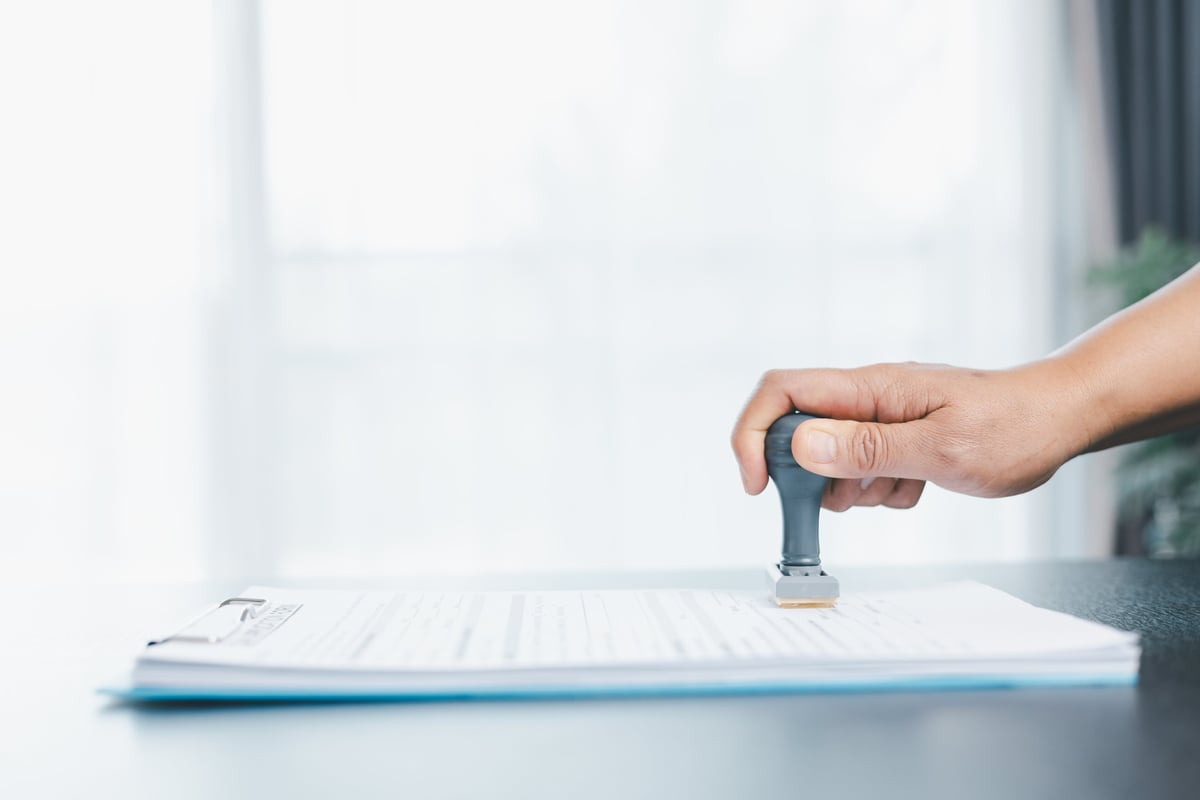 Businessman hands stamp approve on financial business approval document paper. Man hand accepted permit contract agreement. Broker manager sign contract bank guarantee approved stamp application form