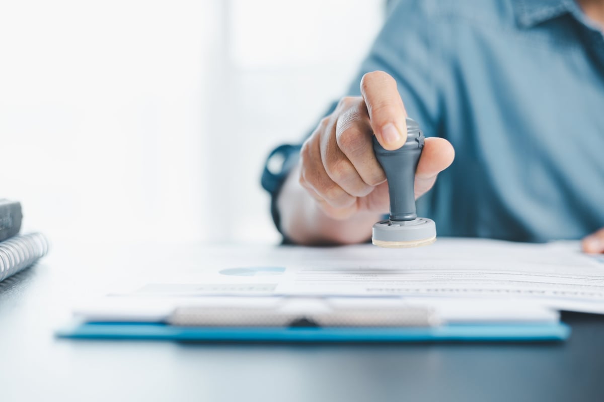 Businessman hands stamp approve on official document paper